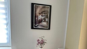 A small, white dining area with two chairs and a table, a framed picture on the wall, and a vase with flowers on the table. - Hotel Süden (Berlin)