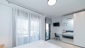 Une chambre d’hôtel moderne dotée d’un grand lit, d’un fauteuil, d’une télévision et d’un balcon avec vue.