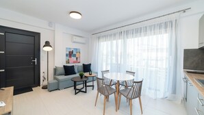 Un salon moderne comprenant un canapé, une table à manger avec des chaises, une petite table d’appoint et une lampe.