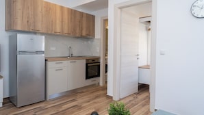 A modern kitchen with wooden cabinets, stainless steel appliances, and a marble backsplash.