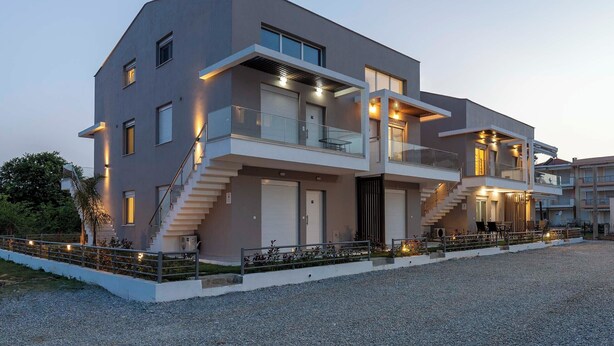 A modern two-story house with a balcony, a staircase, and a driveway.