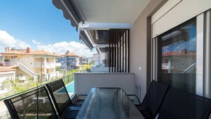 Un balcon avec une table et des chaises, donnant sur un quartier résidentiel avec des maisons et une piscine.