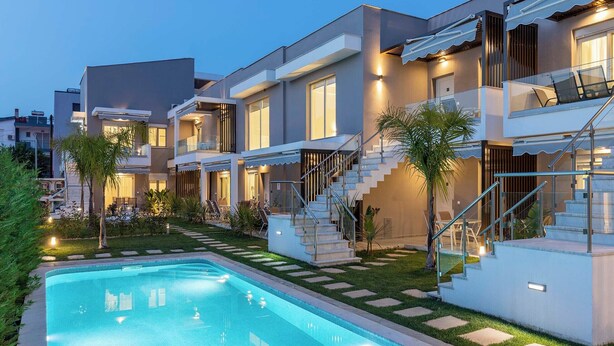 Un immeuble résidentiel moderne doté d’une piscine, de nombreux balcons et d’un escalier bien éclairé.
