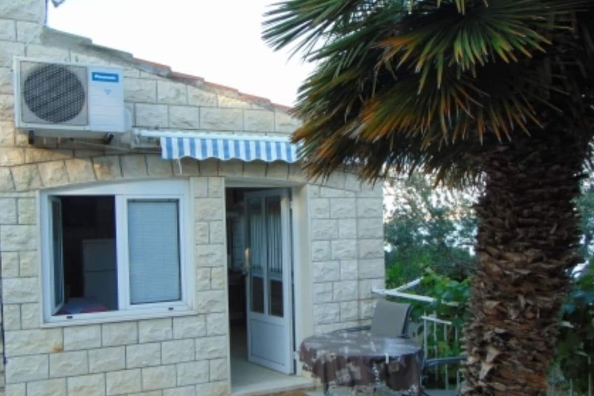 A stone building with a window, a door, and an air conditioning unit.