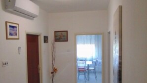 Un couloir avec, au fond, un espace repas comprenant une table et des chaises.