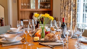 A dining table set with wine glasses, plates, and a loaf of bread. - Cottage in Cornwall near Sandy Beach (Rock)