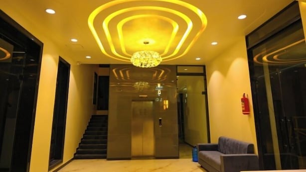 A modern lobby with a staircase, a chandelier, and a sofa. - Hotel Dinanath (Danta Ramgarh)