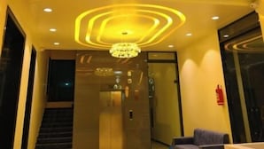 A modern lobby with a reception desk, a staircase, and a chandelier. - Hotel Dinanath (Danta Ramgarh)