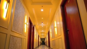 A long, well-lit hallway with marble panels and wooden doors. - Hotel Dinanath (Danta Ramgarh)