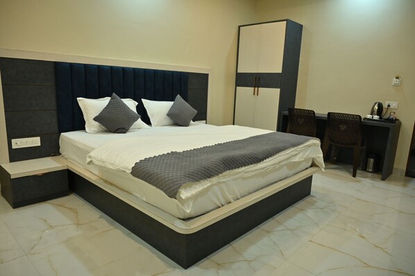A bedroom with a bed, bedside tables, a wardrobe, and a desk with chairs. - Hotel Dinanath (Danta Ramgarh)