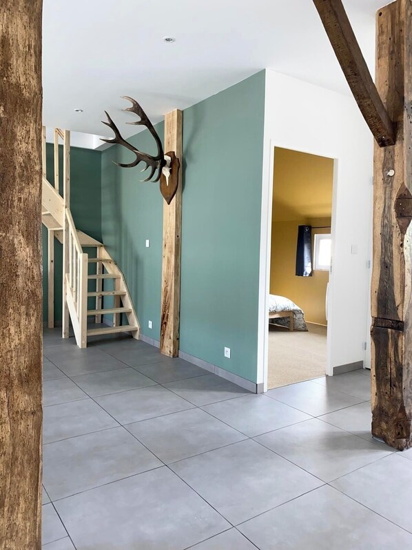 A spacious interior with a staircase, a mounted deer head, and a bed in the adjacent room.