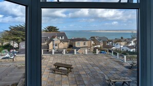 A view from a window overlooking a coastal area with houses, a beach, and a clear sky. - Apartment in St Ives near Porthminster Beach (St Ives)