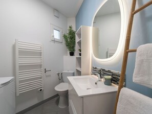 Une salle de bain moderne avec des toilettes blanches, un lavabo et un miroir.