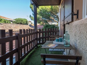 Une terrasse en bois avec une table et un banc, un bocal en verre et une affiche.
