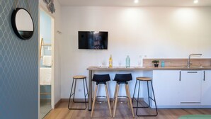 Una cocina moderna con televisor de pantalla plana, taburetes de madera y una barra.