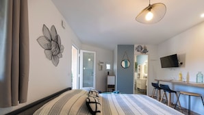 Una habitación de hotel moderna con una cama grande, un escritorio con dos sillas, un televisor y un baño visible a través de una puerta abierta.