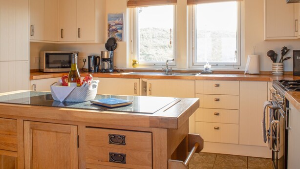Una cucina con mobili in legno, un forno a microonde, un lavello e un piano cottura.