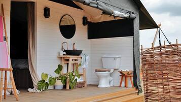 A compact, well-lit wooden cabin with a single bathroom featuring a toilet and sink.
