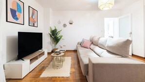 Un salon moderne avec un téléviseur à écran plat, un canapé, une table basse et des œuvres d’art décoratives au mur.