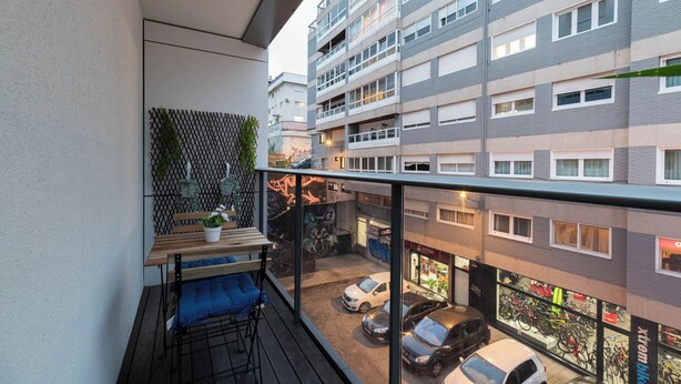 Un balcon avec une table, des chaises et un pot de fleurs.