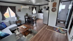 A compact living space with a sofa, coffee table, dining table, and kitchen area.