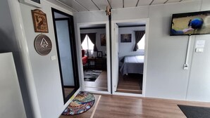 A modern interior with a wooden floor, a bed, a TV, and a door leading to another room.