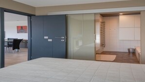 Une chambre moderne avec un lit, une armoire et une porte vitrée donnant sur une salle de bain.