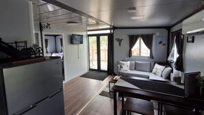 A compact living space with a kitchenette, a dining area, and a seating area with a sofa and chairs.