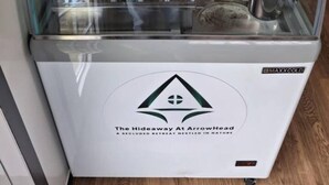 A food display case with various containers of food items, a coffee machine, and a sign indicating a secluded retreat.