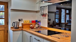 Une cuisine moderne dotée d’un plan de travail en bois, d’appareils électroménagers en acier inoxydable et d’ustensiles suspendus.