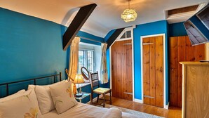 Une chambre à coucher comprenant un lit, une chaise, un bureau, une lampe et des portes en bois.
