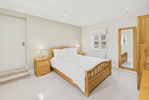 A bedroom with a wooden bed, bedside tables, a window with a view, and a mirror. - Host Stay Blue Barn (Belford)