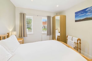Relax in a spacious room with a large bed, a full-length mirror, and a window offering a view of the outside.