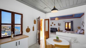 Une cuisine moderne avec vue sur la mer, un coin repas avec une table ronde et un salon avec un canapé et un téléviseur.