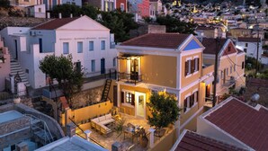 Un immeuble résidentiel à plusieurs étages doté d’un balcon, d’un petit patio aménagé avec du mobilier d’extérieur et d’un escalier menant à un étage supérieur.