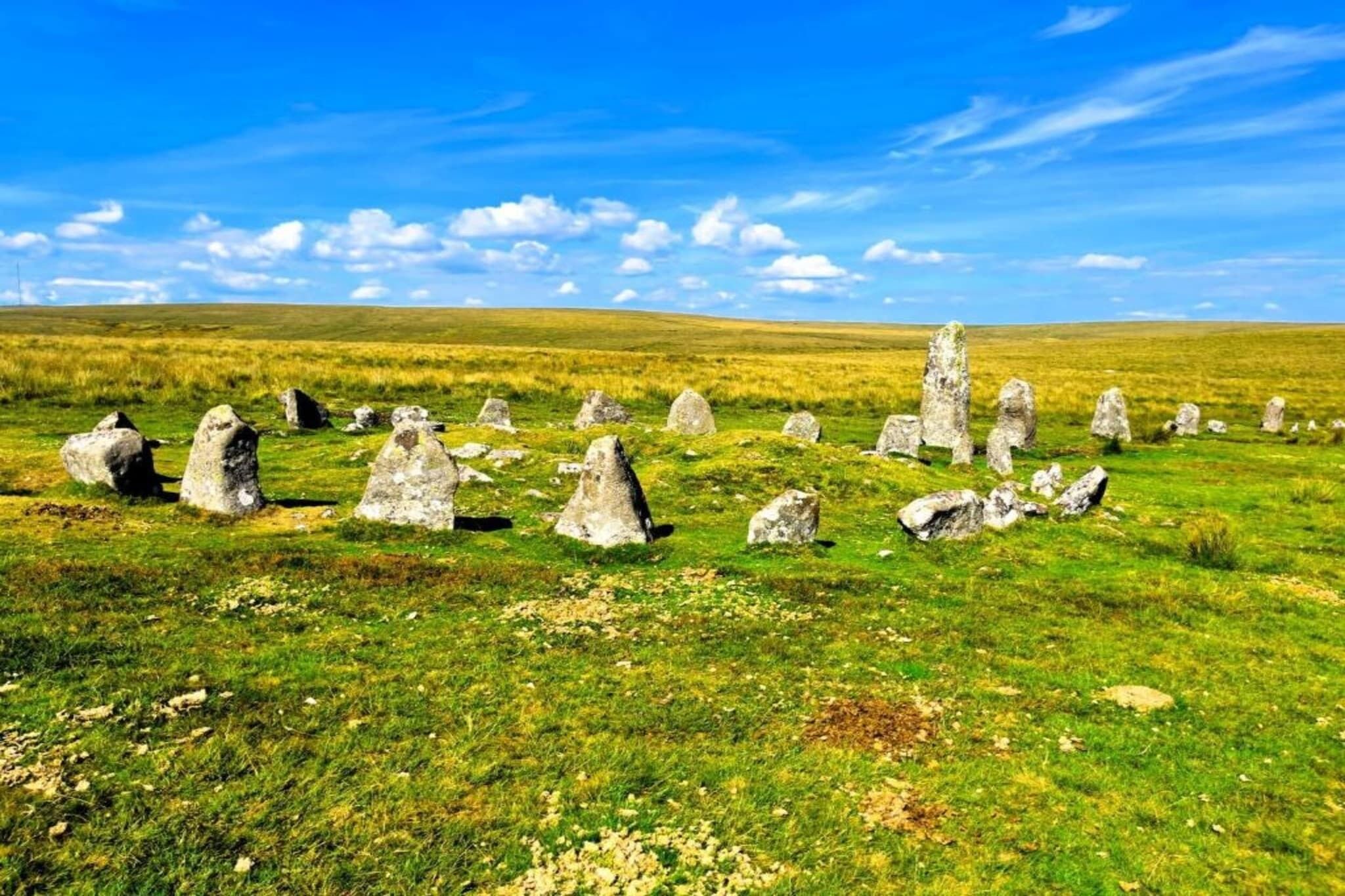 Un círculo de piedras en un campo cubierto de hierba bajo un cielo despejado.