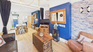 Un salón amplio con una mesa de centro de madera, sofás de cuero, chimenea y una pared decorativa de ladrillo.