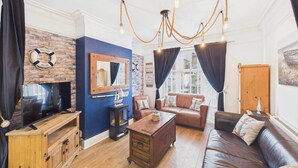 Una sala de estar acogedora con chimenea, un sofá, una mesa de centro y un televisor sobre un mueble de madera.