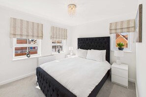 A bedroom with a large bed, white walls, a black headboard, and two bedside tables with lamps. - Host Stay Orient House (Yarm)