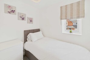 A bedroom with a bed, a dresser, and three wall-mounted floral paintings. - Host Stay Orient House (Yarm)