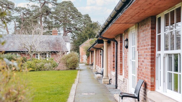 A brick building with a covered walkway and outdoor seating. - 2 bedroom cottage for 4 guests, No Deposit (Dorrington)
