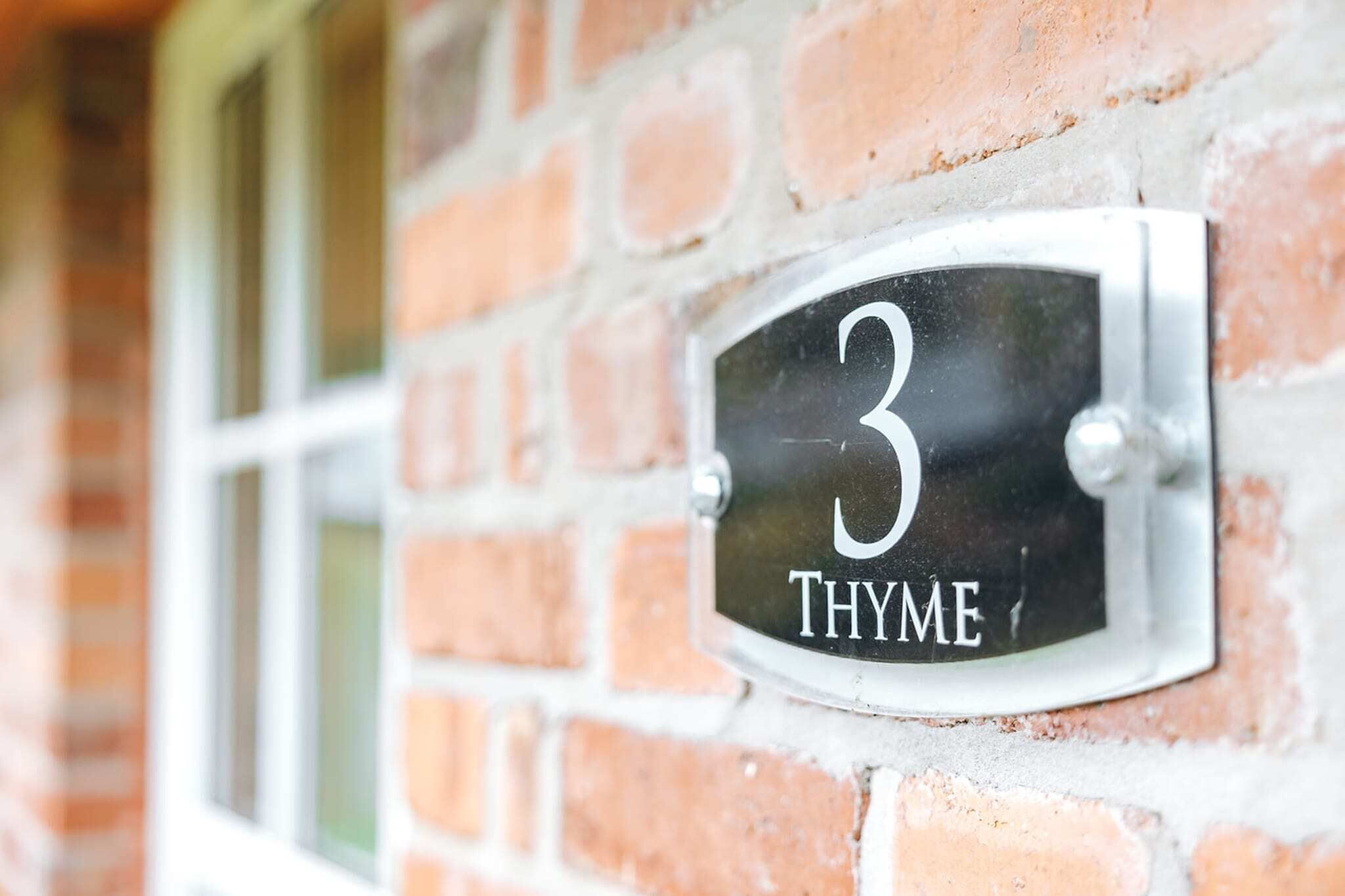 Un panneau indiquant le numéro de la maison, fixé sur un mur de briques.