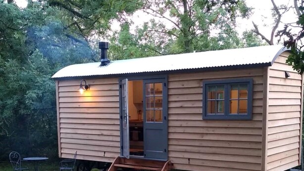 A small wooden cabin with a door, windows, and a light fixture.