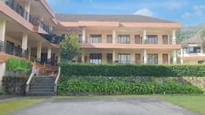 A multi-story hotel with a central courtyard, balconies, and a stone wall. - Hotel O Bogor near Taman Safari formerly Ken Raudhah Inn (Cisarua)
