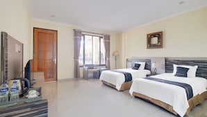 A hotel room with two beds, a desk with a chair, a television, and a minibar. - Hotel O Bogor near Taman Safari formerly Ken Raudhah Inn (Cisarua)