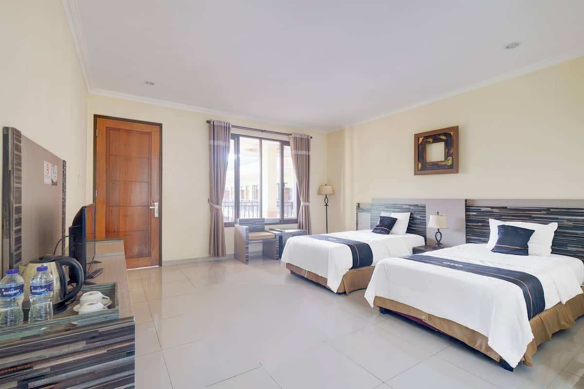 A hotel room with two beds, a desk with a chair, a television, and a minibar.