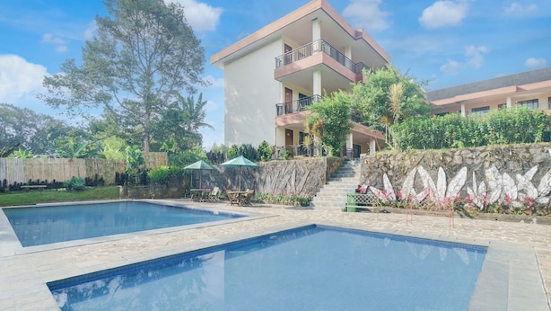 A hotel with a swimming pool, outdoor seating, and a stone wall. - Hotel O Bogor near Taman Safari formerly Ken Raudhah Inn (Cisarua)