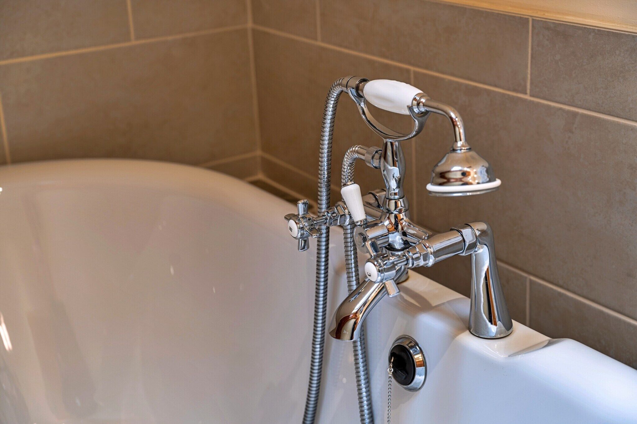Un baño con bañera, ducha de mano y grifo.
