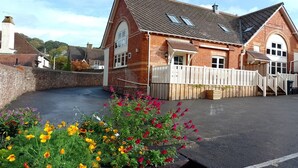 A brick building with a sloped roof, a gated entrance, and a paved driveway. - Cottage in Minehead near Exmoor National Park (Minehead)