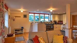 A cozy living room with a sofa, a coffee table, and a view of the kitchen. - Cottage in Minehead near Exmoor National Park (Minehead)